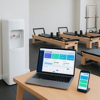 please add an image of a water cooler that doesnt show the water bottle in a gym studio managing software on a laptop and a phone different pilates re